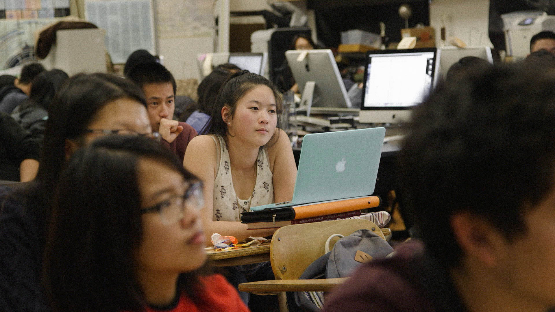Asian American girl listens to lecture with Macbook laptop open