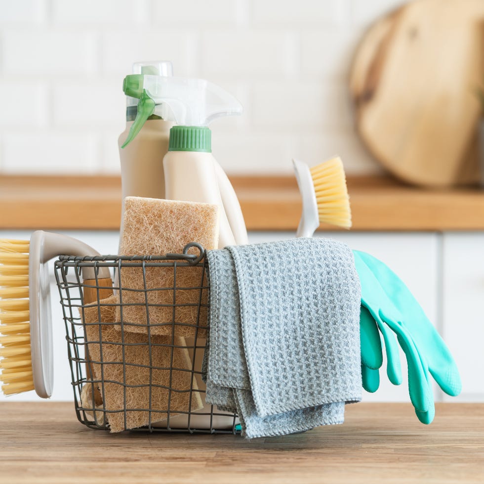 cleaning supplies basket with brushes, rags, natural sponges and cleaning products