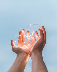 Two hands holding a string of glowing lights